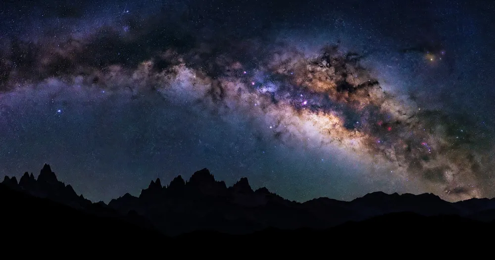 The Milky Way over dark mountain silhouettes at night