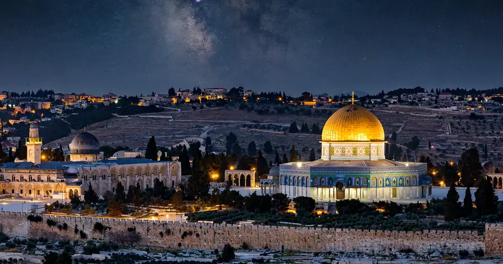 The Al-Aqsa Mosque in Jerusalem at night under a starry sky, destination of the Night Journey
