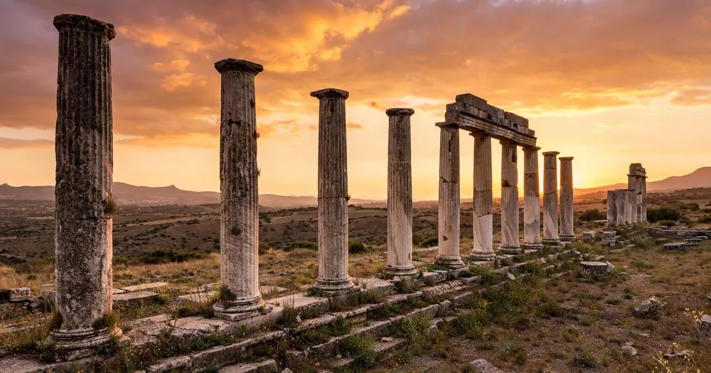 Ancient Roman stone columns standing against a warm sunset sky