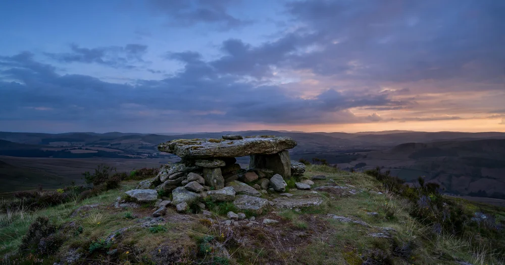 A stone altar on a hilltop under a wide sky at dusk