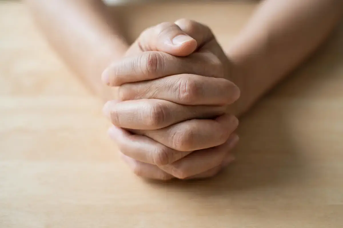 Hands folded in gratitude over a cleared table