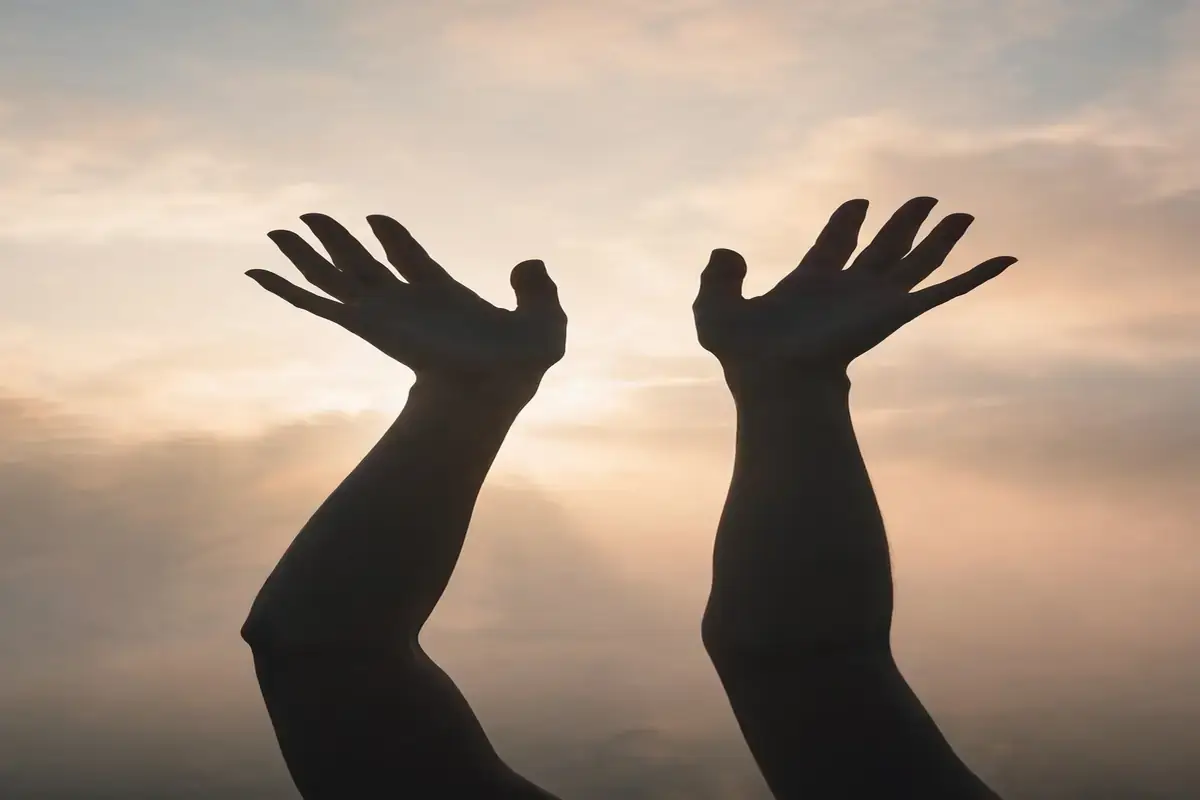 Hands raised in gratitude against soft morning light