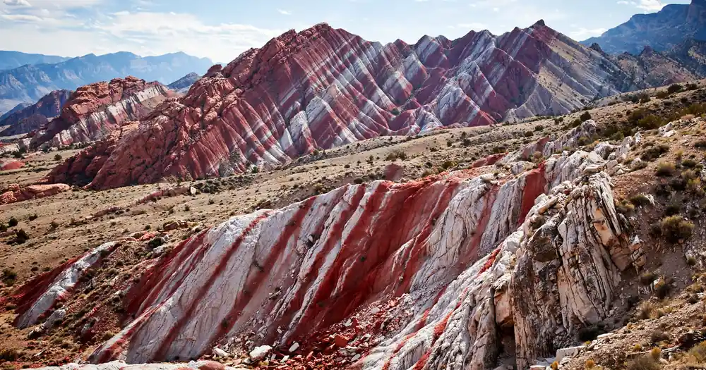 Mountains with streaks of white and red rock under a bright sky