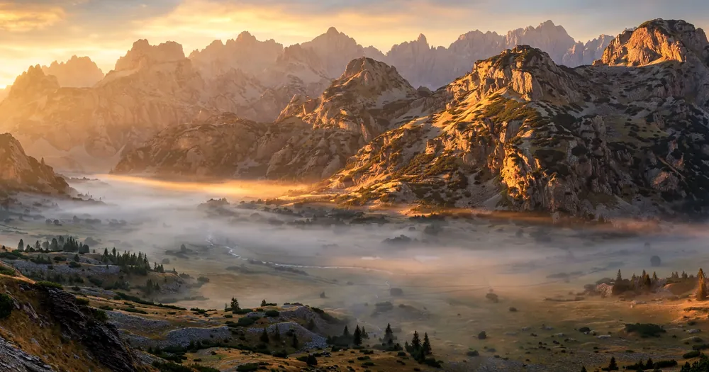 Rugged mountains glowing at sunrise above a quiet valley