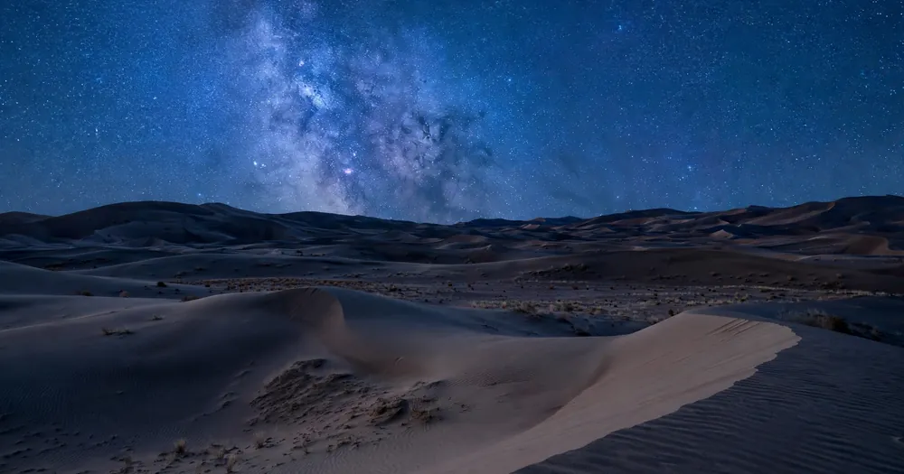 Starry night sky over desert dunes, reflecting the cosmic signs in Surah Yaseen